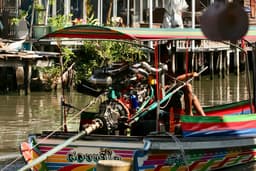 A longtail boat on a canal lined with wooden stilt houses in Bangkok