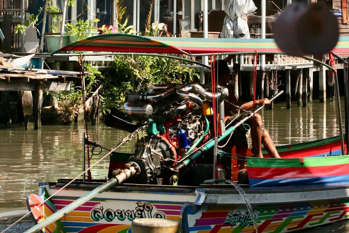 A longtail boat on a canal lined with wooden stilt houses in Bangkok