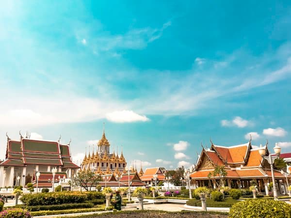 Temple roofs and golden spires in Bangkok under a blue sky