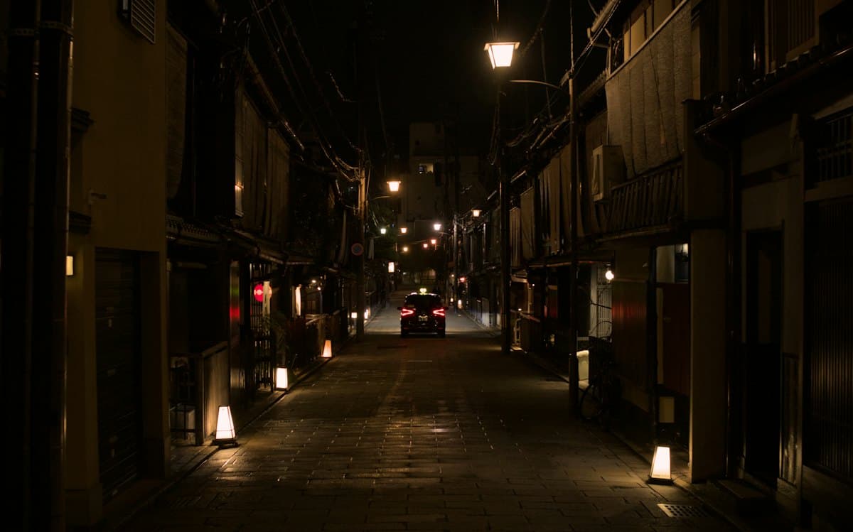 A quiet lane in Kyoto's Gion district at night, lit by paper lanterns